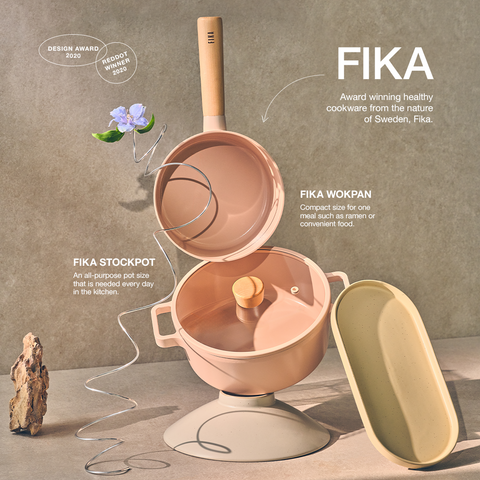Award-winning FIKA cookware collection set against a natural textured background, including a stockpot, wok pan, and serving dishes in earthy tones, with a design award badge, emphasizing the all-purpose size and convenience for everyday cooking