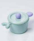 A pastel-colored pot with a light green body and a purple handle and lid, displayed on a white background