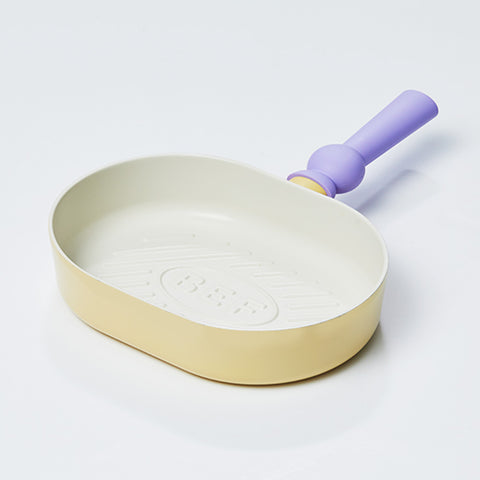 A pastel-colored grill pan with a yellow body and a purple handle, displayed on a white background