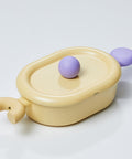 An oval pastel-colored pot with a yellow body and a purple handle, displayed on a white background