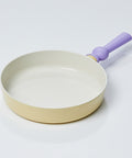 A pastel-colored frypan with a yellow body and a purple handle, displayed on a white background