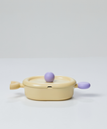 A yellow oval pot with a lid and purple handles, displayed on a white background.