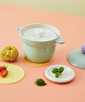 Mint rice pot with a ceramic steam lid, fresh basil leaves, cherry tomatoes, and a decorative pumpkin in a pastel-colored setting."

Keywords: steam pot, rice cooker, cooking pot, ceramic kitchenware, pastel kitchen decor