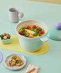 Pastel mint ceramic pot filled with fresh vegetables, paired with aesthetic dishware and decorative table settings."

Keywords: kitchen decor, ceramic rice cooker, aesthetic dining, cooking pot, pastel kitchen items