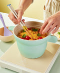 Induction-compatible ceramic rice pot, cooking corn and cherry tomatoes, with a lavender-colored serving spoon, practical and stylish cookware."

Keywords: induction pot, ceramic kitchenware, multipurpose pot, cooking essentials, stylish kitchen items