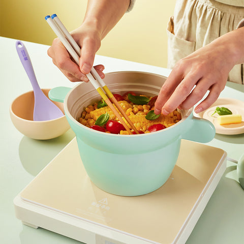 Induction-compatible ceramic rice pot, cooking corn and cherry tomatoes, with a lavender-colored serving spoon, practical and stylish cookware."

Keywords: induction pot, ceramic kitchenware, multipurpose pot, cooking essentials, stylish kitchen items