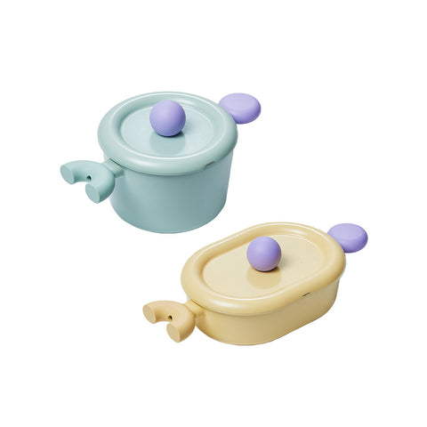 A set of two pastel-colored cookware items, including a light green pot with a lid and a yellow oval pot with a lid, both with purple handles, displayed on a white background